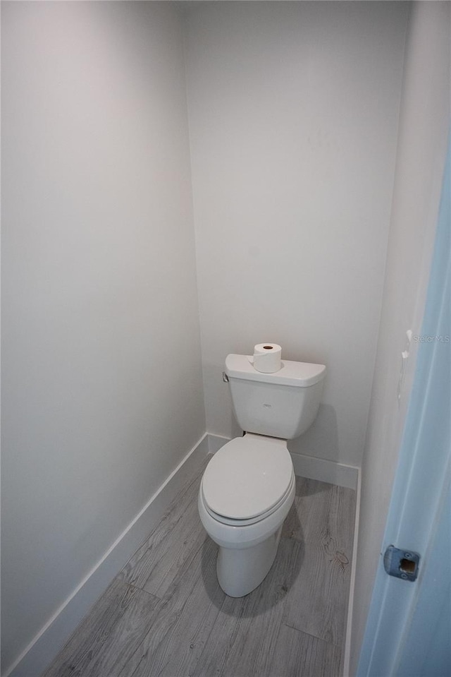 bathroom featuring toilet, baseboards, and wood finished floors