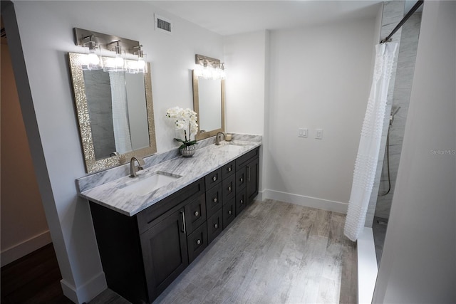 bathroom featuring double vanity, visible vents, a sink, and wood finished floors