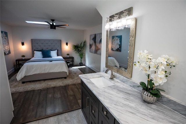 bedroom with ceiling fan, baseboards, a sink, and wood finished floors