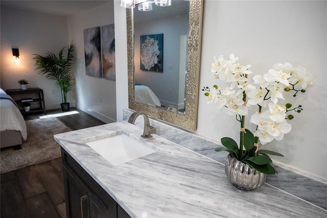 ensuite bathroom featuring baseboards, vanity, ensuite bath, and wood finished floors