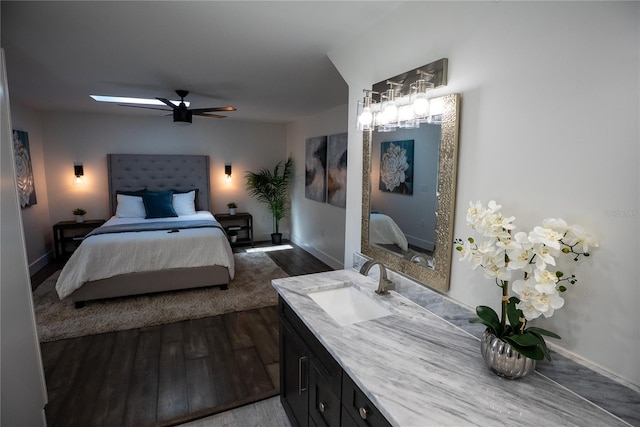 bedroom featuring ceiling fan, a sink, dark wood finished floors, and baseboards