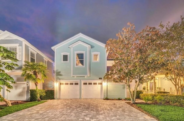 view of front facade featuring a garage, decorative driveway, and stucco siding