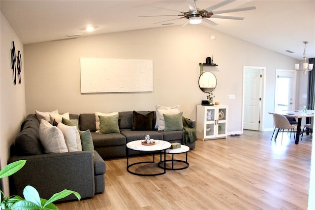 living area featuring lofted ceiling, light wood finished floors, ceiling fan with notable chandelier, and visible vents