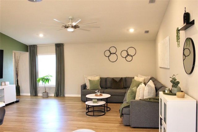 living room with visible vents, a ceiling fan, vaulted ceiling, baseboards, and light wood-type flooring