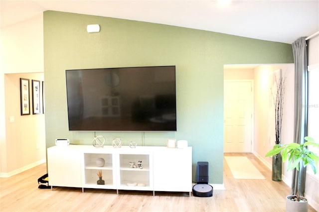 interior space featuring lofted ceiling, baseboards, and wood finished floors