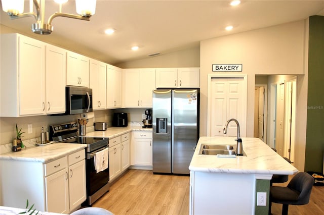 kitchen with lofted ceiling, light wood-style flooring, a sink, white cabinets, and appliances with stainless steel finishes