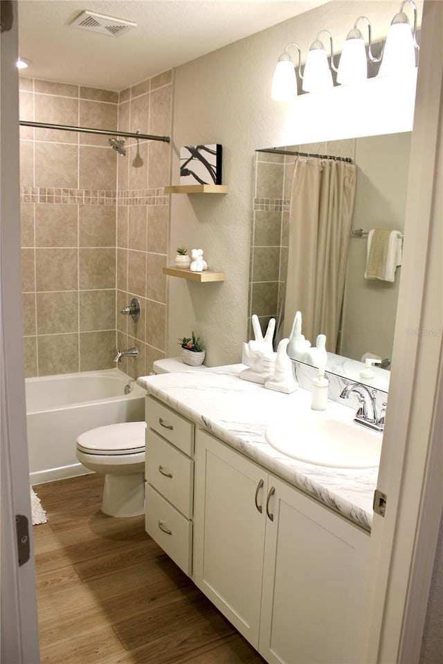 bathroom with shower / bath combo, visible vents, toilet, wood finished floors, and vanity