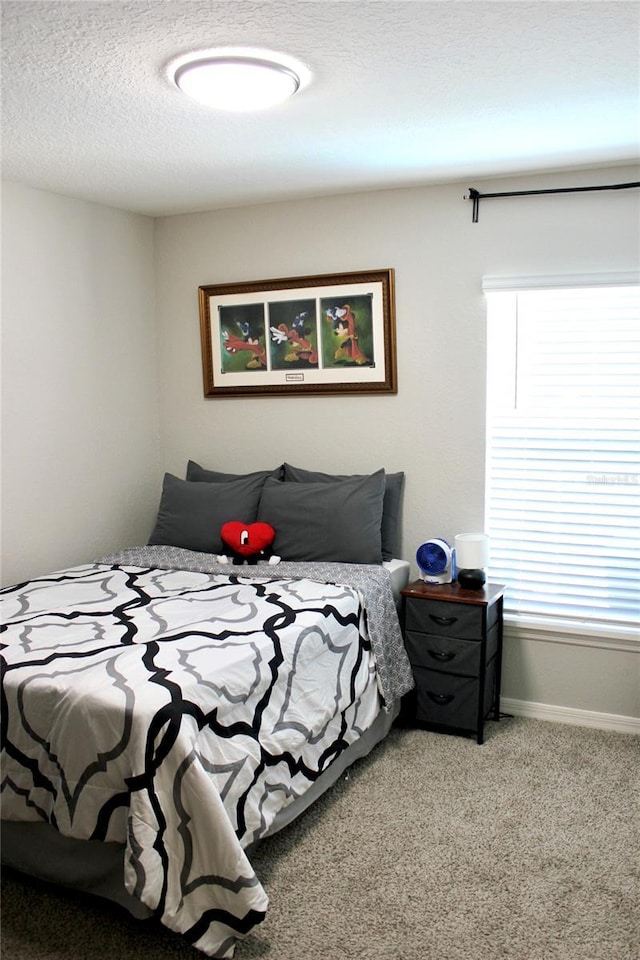 bedroom with a textured ceiling, carpet flooring, and baseboards