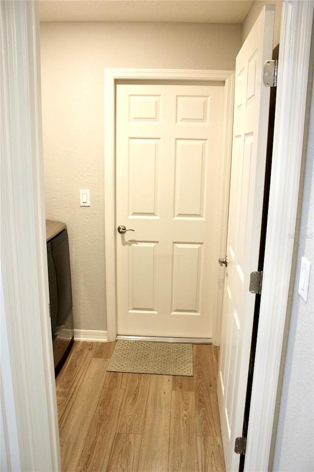 laundry room with laundry area, baseboards, washer / clothes dryer, and light wood finished floors