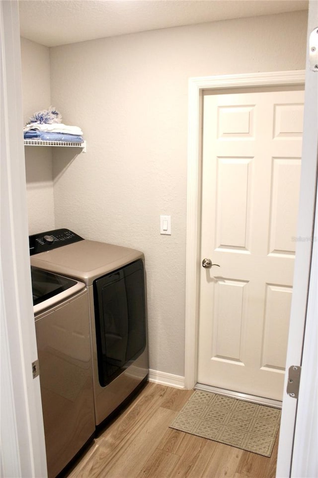 clothes washing area with laundry area, light wood-style flooring, baseboards, and independent washer and dryer