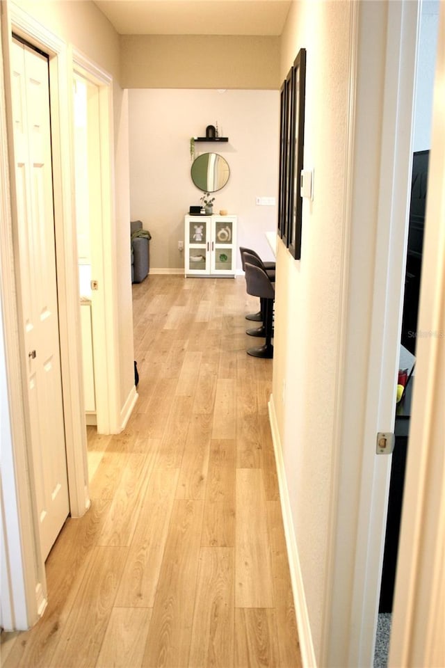 hallway featuring baseboards and light wood finished floors