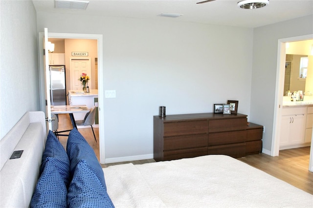 bedroom featuring light wood-type flooring, ensuite bath, visible vents, and baseboards