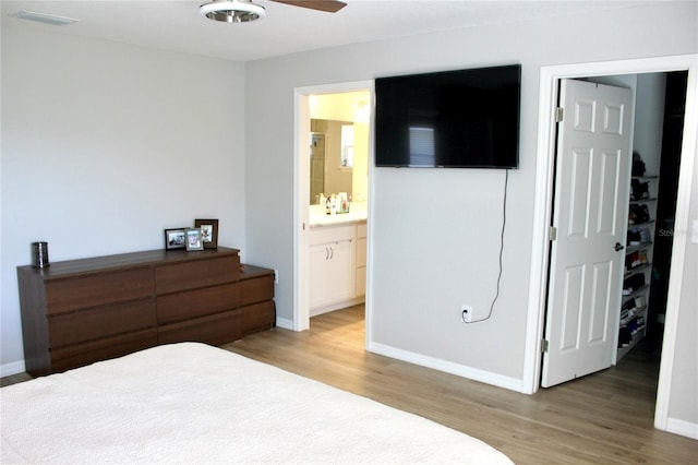 bedroom featuring visible vents, connected bathroom, baseboards, and wood finished floors