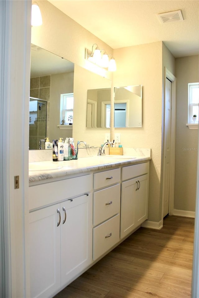 bathroom with a sink, a shower stall, visible vents, and wood finished floors