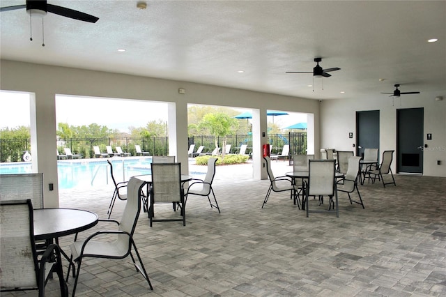 view of patio / terrace with ceiling fan, outdoor dining space, fence, and a community pool