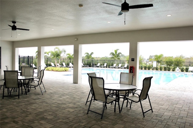 view of patio / terrace with ceiling fan, a community pool, fence, and outdoor dining space