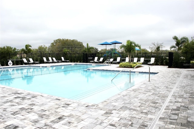 community pool with a patio area and fence