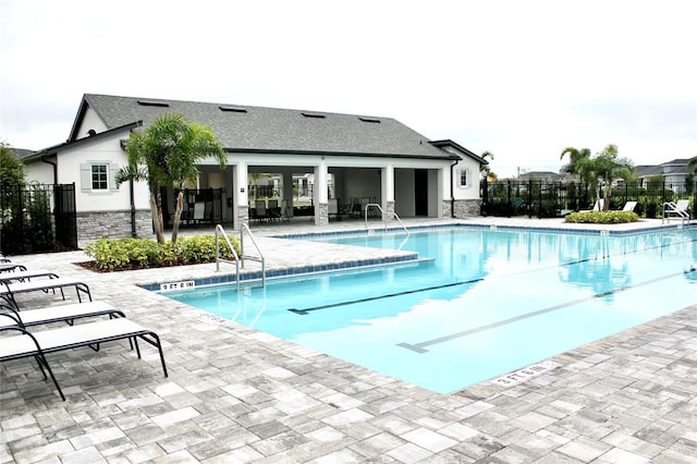 community pool with a patio area and fence