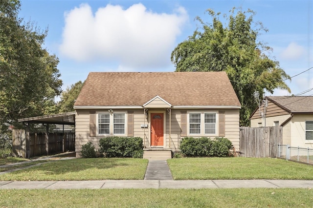 bungalow with roof with shingles, fence, a carport, and a front yard