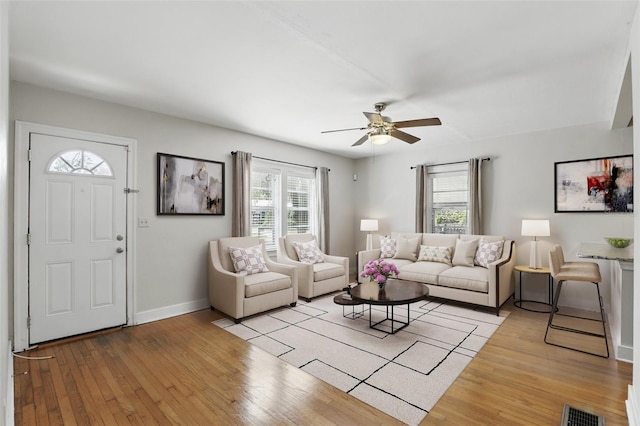 living room with light wood finished floors, baseboards, visible vents, and a wealth of natural light