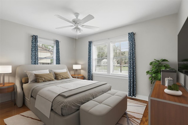 bedroom with a ceiling fan, baseboards, and light wood finished floors