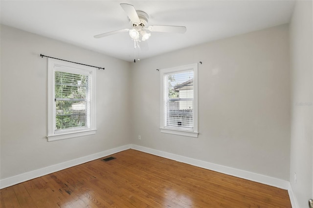 unfurnished room featuring ceiling fan, wood finished floors, visible vents, and baseboards