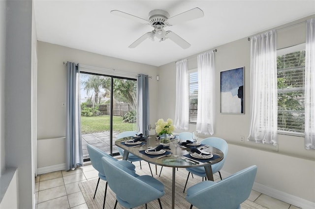 dining space featuring light tile patterned floors, a ceiling fan, baseboards, and a wealth of natural light