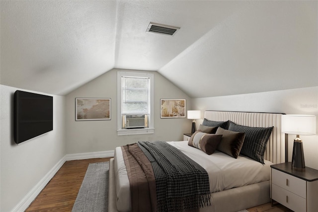 bedroom featuring a textured ceiling, dark wood-type flooring, visible vents, baseboards, and vaulted ceiling