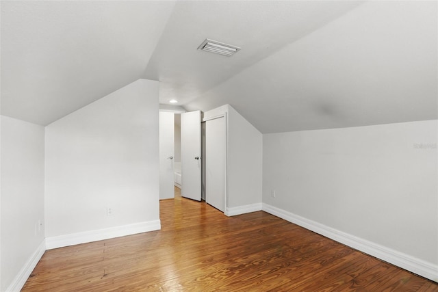 bonus room featuring lofted ceiling, light wood-style flooring, visible vents, and baseboards