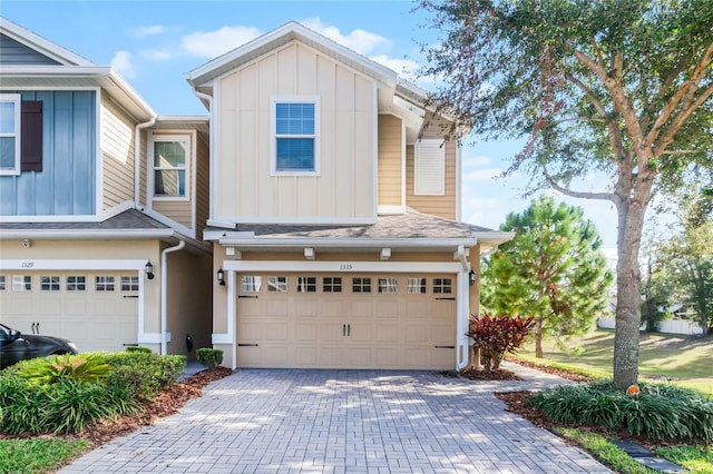 view of front of home with board and batten siding, decorative driveway, a shingled roof, and a garage