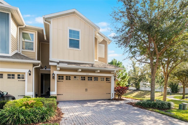 townhome / multi-family property featuring a garage, decorative driveway, board and batten siding, and a shingled roof