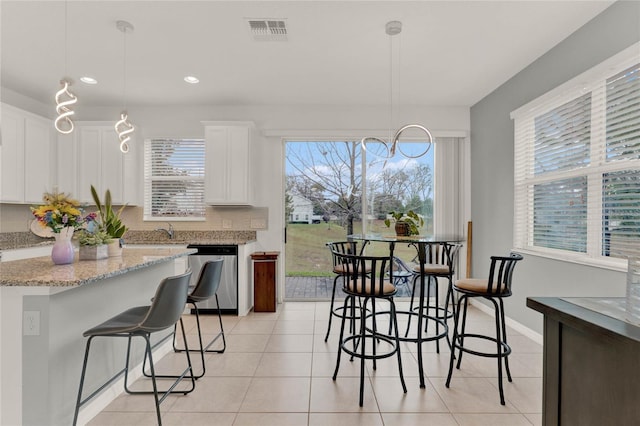 kitchen featuring white cabinetry, visible vents, stainless steel dishwasher, and light tile patterned flooring