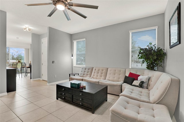 living area with a ceiling fan, baseboards, and light tile patterned floors