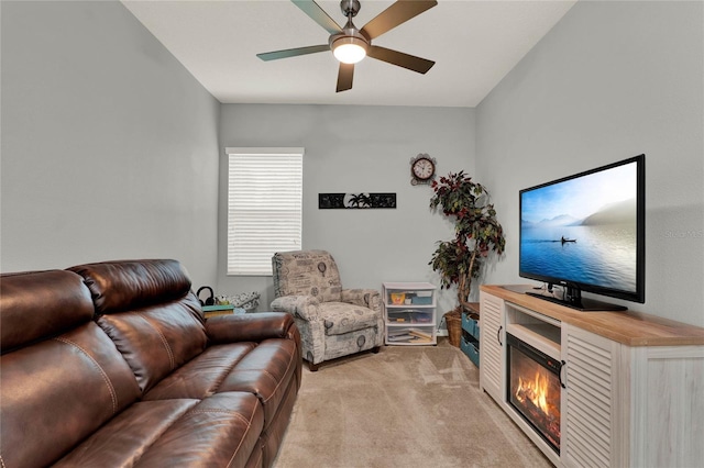 living room with a ceiling fan, a glass covered fireplace, and light colored carpet