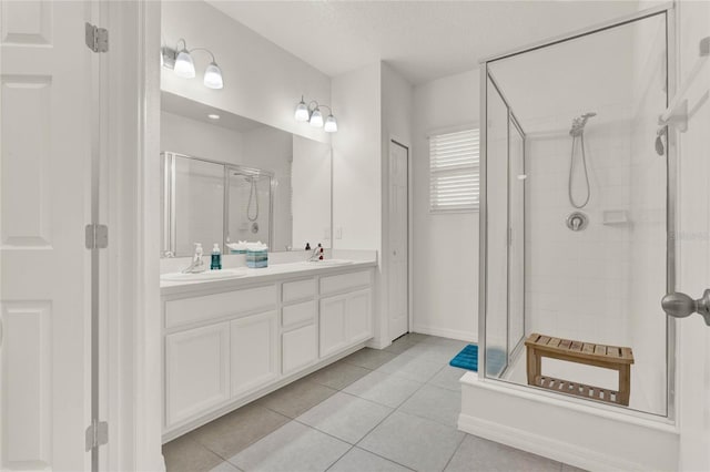 full bathroom featuring a textured ceiling, a sink, tile patterned floors, double vanity, and a stall shower