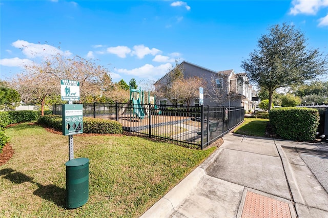 view of community featuring playground community, fence, and a lawn