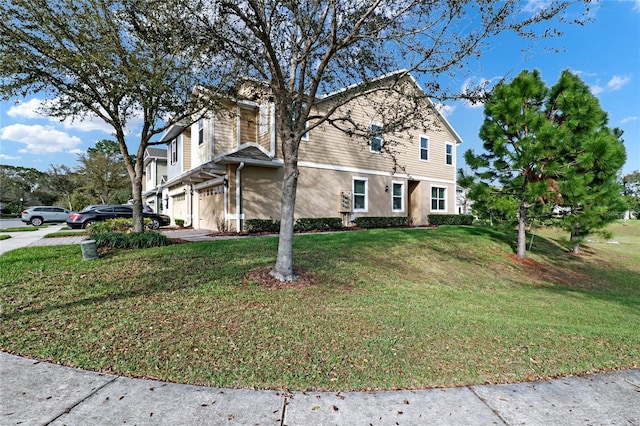 view of front facade with an attached garage, stucco siding, and a front yard