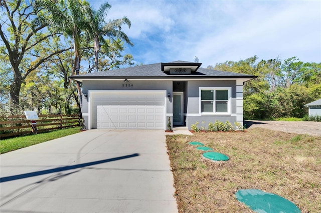 view of front of house with a garage, concrete driveway, fence, and stucco siding