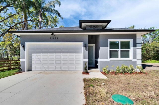 view of front of property with an attached garage, driveway, fence, and stucco siding