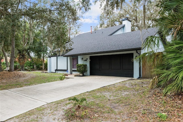 view of front of home with an attached garage, a shingled roof, driveway, stucco siding, and a chimney