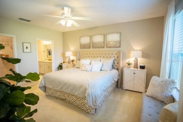 carpeted bedroom featuring a ceiling fan, visible vents, and connected bathroom