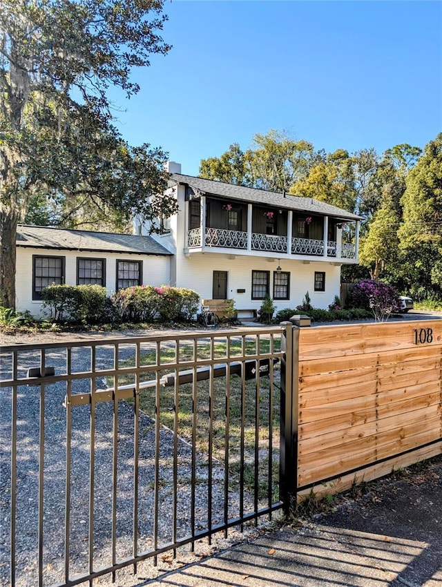 view of front facade with a fenced front yard, a gate, and a balcony