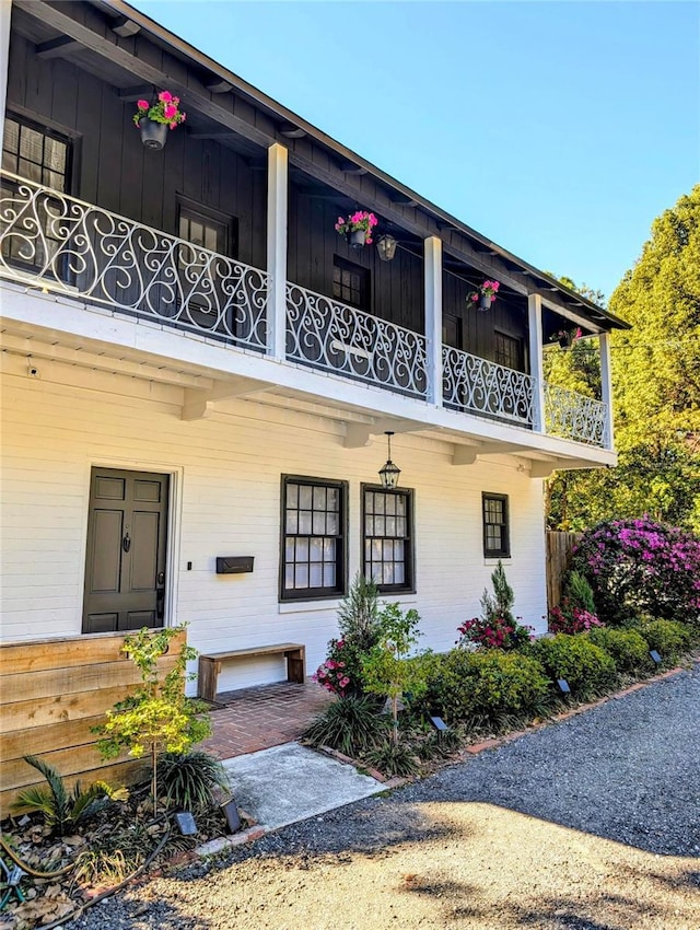 entrance to property with covered porch, brick siding, and a balcony