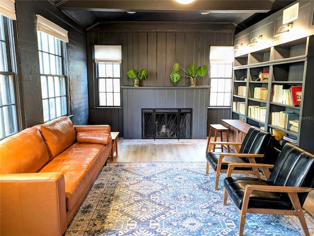 living area featuring a wealth of natural light, brick wall, a fireplace, and wood finished floors
