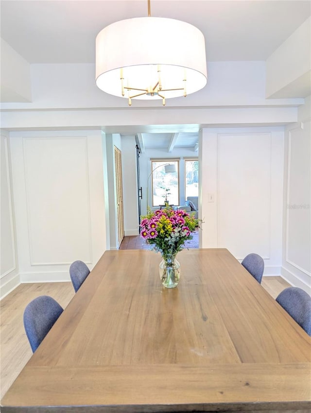 dining space with a chandelier, a decorative wall, and light wood-style flooring
