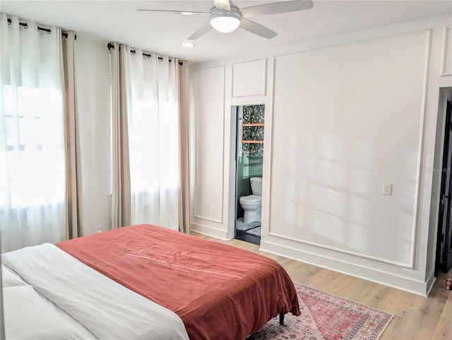 bedroom with light wood-style flooring, baseboards, ceiling fan, and ensuite bathroom