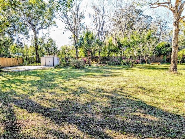view of yard with a storage shed, fence, and an outdoor structure