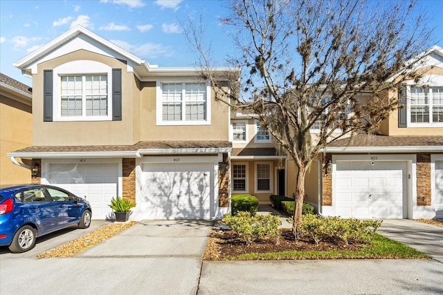 multi unit property featuring stone siding, an attached garage, driveway, and stucco siding