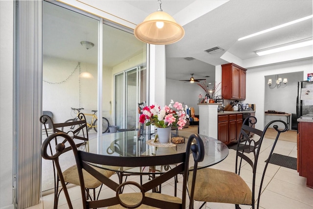 dining room with light tile patterned floors, visible vents, and ceiling fan with notable chandelier