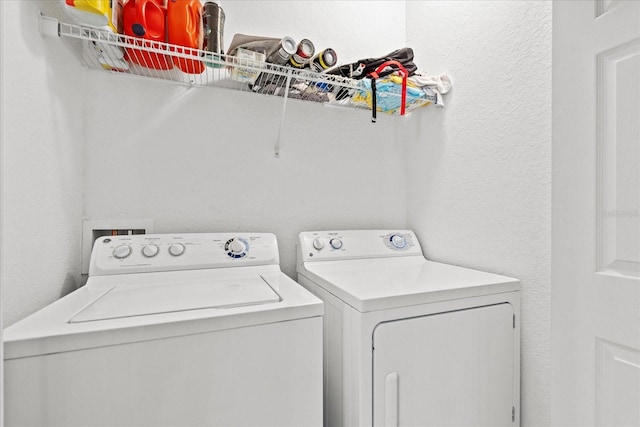 clothes washing area featuring laundry area, a textured wall, and separate washer and dryer